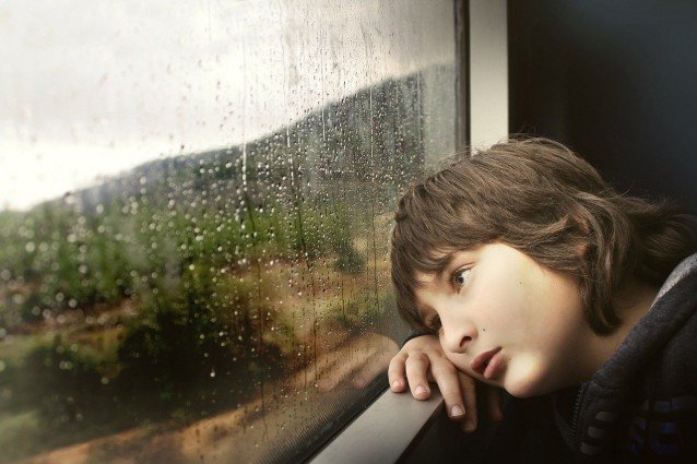 Junge vor Fenster im Regen